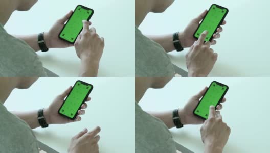 男人使用，滚动和看智能手机的绿色屏幕和色度键在家里高清在线视频素材下载