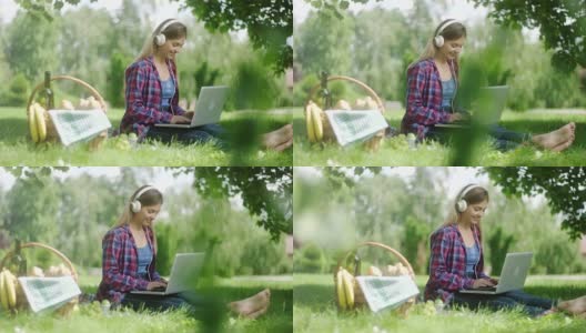 一个女人在野外用笔记本电脑和耳机野餐高清在线视频素材下载