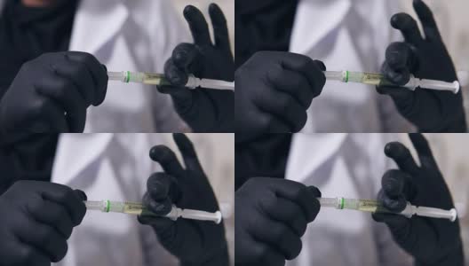 特写镜头专业医生的手在黑色手套与医疗注射器在手中，准备注射高清在线视频素材下载