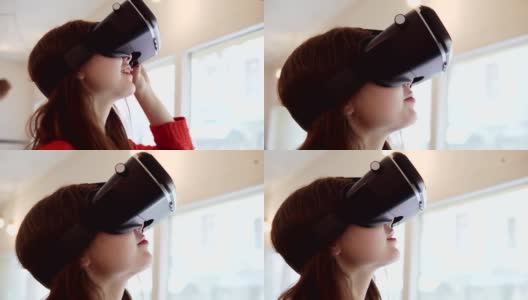 漂亮的黑发女人使用她的手机VR耳机在咖啡馆。可负担得起的虚拟现实眼镜。4 k替身视频高清在线视频素材下载