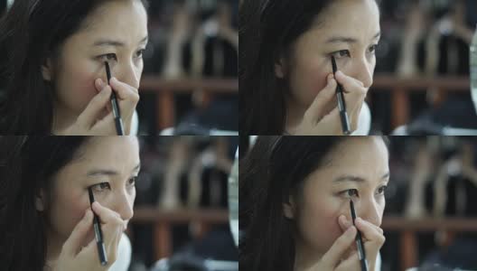 亚洲女人在镜子前化妆，画眼线的慢动作。美容化妆概念高清在线视频素材下载