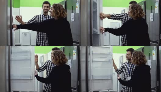 在一家消费电子商店购买前，一名年轻女子站在打开冰箱的门，与一名男性顾问讨论冰箱的设计和质量。与商店顾问讨论特点高清在线视频素材下载