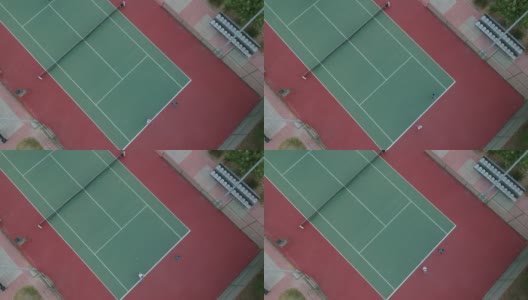 一个男孩和一个女孩正在做网球练习在硬地球场高清视频无人机的观点高清在线视频素材下载