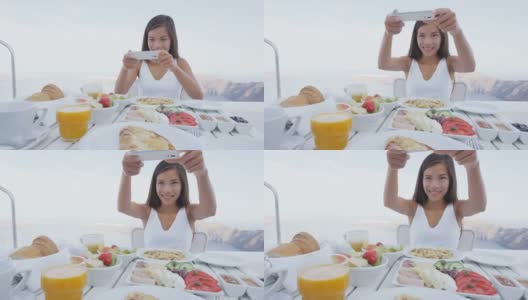 一个女人用手机app拍早餐。一个女孩用社交媒体拍豪华旅行度假的食物。欧洲希腊圣托里尼度假胜地的美女。高清在线视频素材下载