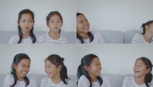 两个亚洲小女孩的肖像看着相机，微笑着，在客厅幸福地一起笑。慢动作50 FPS。高清在线视频素材下载