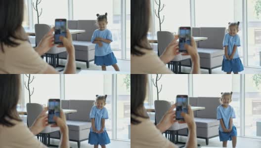 年轻女子拿着智能手机给女儿拍照高清在线视频素材下载