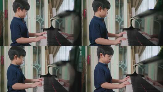 侧视亚洲男孩在客厅里弹钢琴。有选择性的重点。孩子专心上课。业余爱好和在家学习。快乐的一天和家庭的概念。活动和生活方式。高清在线视频素材下载
