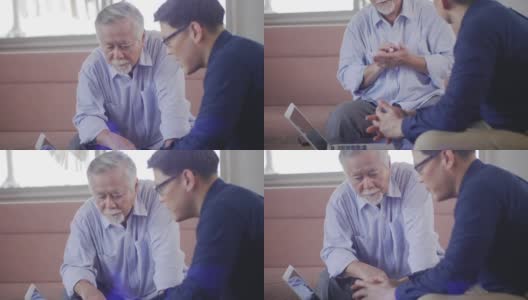 英俊的亚洲男员工坐在客厅里和一位老人聊天。讲解退休后的健康保险高清在线视频素材下载
