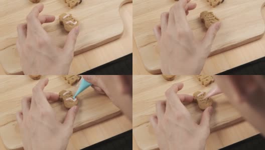 厨师拿起和挤压糖奶油圣诞自制姜饼雪人饼干在木制托盘上的特写高清在线视频素材下载