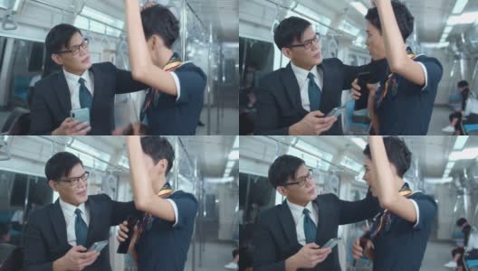 一名亚洲男子和一名白人女子乘坐地铁上下班，用智能手机观看视频高清在线视频素材下载