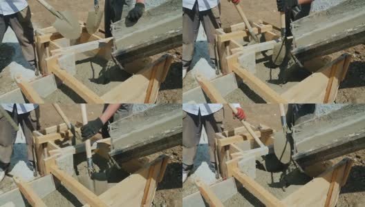 在建筑工地使用混凝土。工人们把混凝土放进一个木模里。建筑工地繁重的体力劳动高清在线视频素材下载