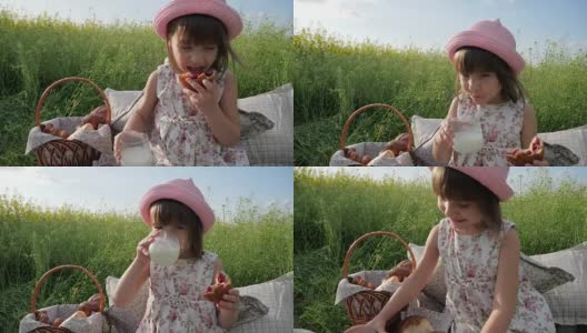 野餐自然，可爱的小女孩肖像吃百吉饼，生面团产品，喝牛奶在日落，孩子在家庭野餐高清在线视频素材下载