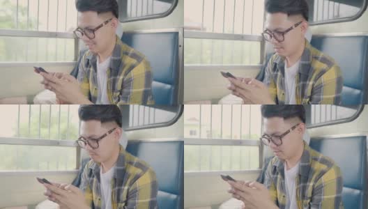 一名亚洲男子在坐火车时用智能手机查看社交媒体。高清在线视频素材下载