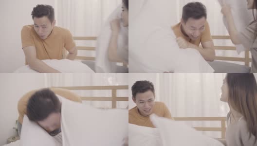 亚洲夫妇在卧室的床上玩枕头大战，妻子和丈夫在家里躺在床上享受有趣的时刻。夫妻在家里放松享受爱的时刻的概念。高清在线视频素材下载