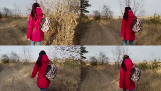 年轻女子走在人行道上。春日里，背着五颜六色背包的年轻女子走在乡间小路上的背影高清在线视频素材下载