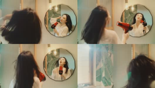 令人难以置信的感觉。亚洲民族妇女享受早晨的浴室常规和在镜子前的乐趣。吹干头发跳舞高清在线视频素材下载
