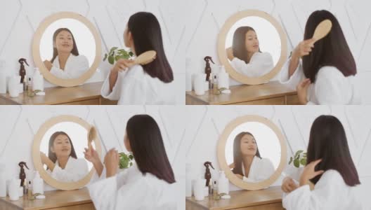 每天都美丽。年轻迷人的和平亚洲女士梳理她的头发与刷子，看着镜子在卧室高清在线视频素材下载
