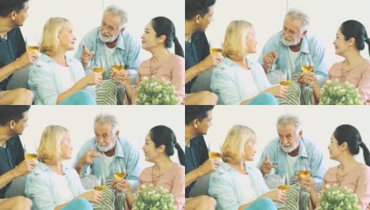 一个老人在客厅里喝着白葡萄酒和妻子聊天。白人，亚洲人，泰国人坐在家里的沙发上。退休生活方式的概念。高清在线视频素材下载