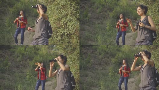 年轻女性在山林中徒步旅行时使用双筒望远镜。高清在线视频素材下载