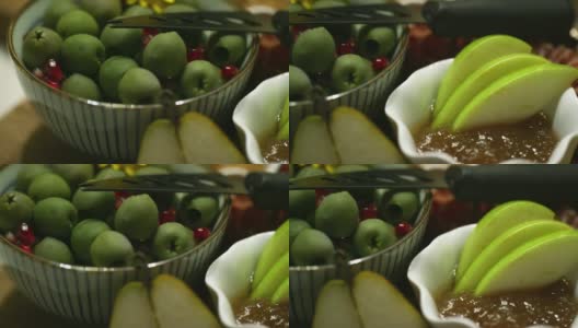 室内庆祝/派对上，用平底锅近距离平底锅拍摄的绿橄榄和石榴(种子)在一个装饰碗里，旁边是一碗蜜饯和苹果片，餐刀放在开胃盘的顶部高清在线视频素材下载