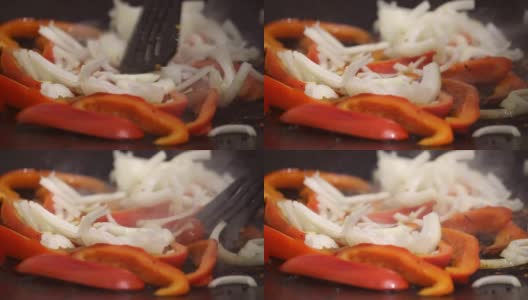 一碟蔬菜片。辣椒和洋葱在煎锅里炸，用热油或油，在明火上煮。高清在线视频素材下载