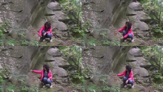 一个女孩在山上的一块岩石上进行地质勘探高清在线视频素材下载