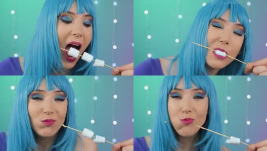 蓝色头发的年轻女孩在吃美味的棉花糖高清在线视频素材下载
