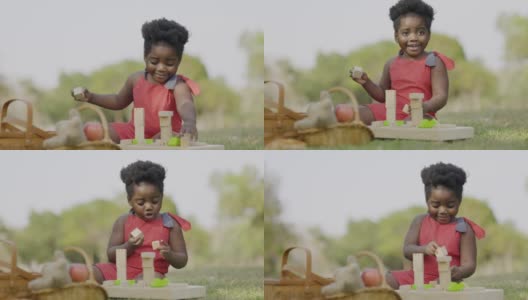非裔美国女孩坐在木制玩具快乐的夏天花园。学龄前儿童快乐成长。技能还记得。周末活动快乐家庭生活理念。概念儿童节高清在线视频素材下载