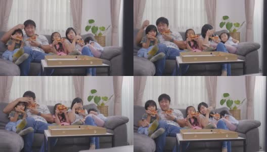 快乐的亚洲家庭喜欢在假日里坐在沙发上吃披萨和看电视高清在线视频素材下载