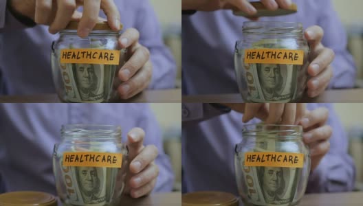 一个白人男人把一个玻璃罐子放在抽屉里，里面装着他未来的医疗储蓄高清在线视频素材下载