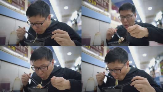 一名亚洲男子在餐厅吃香港汤面高清在线视频素材下载