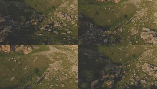 沿着岩石悬崖飞行在山脚下的史诗峭壁的高原在北高加索。以4k / 100mbps的速度飞过布满石头的绿色田野高清在线视频素材下载