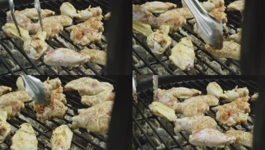 在户外烧烤架上，一个人用一把金属钳子将调味过的鸡翅翻转过来高清在线视频素材下载