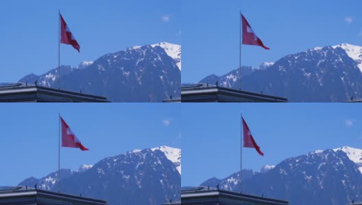 瑞士国旗在阿尔卑斯山脉的背景站在房子的屋顶高清在线视频素材下载
