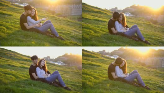 爱的年轻夫妇一起坐在草地上，夕阳在背景高清在线视频素材下载
