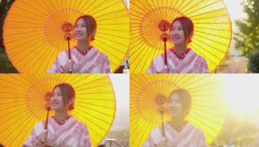 慢镜头近距离拍摄微笑的年轻美丽的亚洲女性游客穿着传统的日本和服拿着红纸伞享受旅游度假秋天在东京城市，日本高清在线视频素材下载