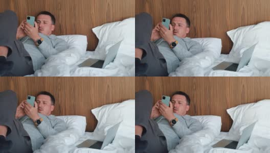 一个男人躺在酒店房间的床上给手机充电高清在线视频素材下载