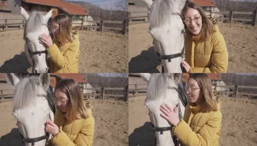可爱的有爱心的年轻女子，在动物救援中心爱抚和亲吻白色种马高清在线视频素材下载