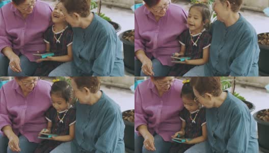 近距离观看两位亚洲老奶奶和孙女玩智能手机的4K视频，感受互联网技术与现代生活中人们的联系。高清在线视频素材下载