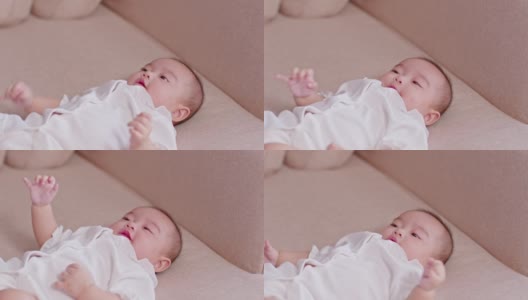 可爱的亚洲女婴躺在床上看着相机。可爱的小婴儿微笑着，幸福放松在床上。亚洲婴儿在卧室新生肖像，软焦点高清在线视频素材下载