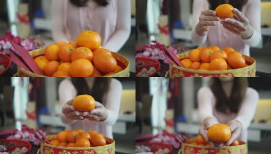 亚洲华人微笑的妇女手拿桔子在生活大厅在中国新年高清在线视频素材下载