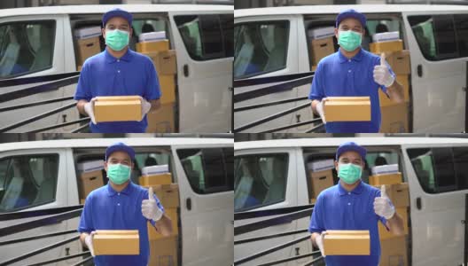 冠状病毒概念，蓝色快递英俊的亚洲男子拿着包裹纸盒，竖起大拇指，戴着防护面具和医用橡胶手套站在货车前面。慢动作镜头。高清在线视频素材下载