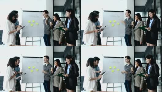 在现代办公室开会期间，年轻的商业人士在白板上用便利贴与他们的同事分享商业战略计划的想法。高清在线视频素材下载