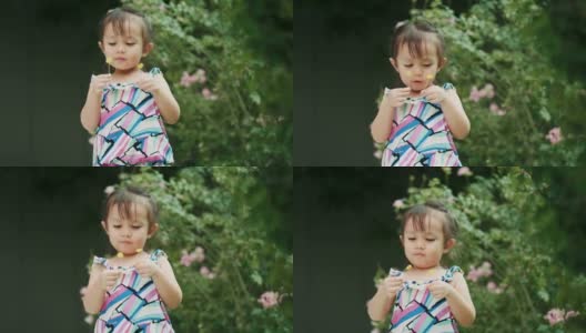 泰国可爱的小女孩抱着花，在花园里闻着花香高清在线视频素材下载