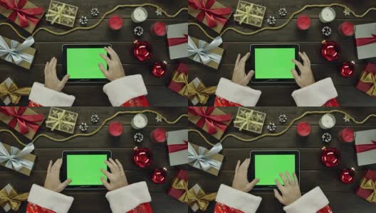 圣诞老人用绿色屏幕的平板电脑被圣诞假期书桌，自上而下拍摄高清在线视频素材下载