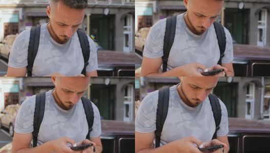 一个留着胡子的年轻人坐在外面的栏杆上，用手机查看邮件高清在线视频素材下载