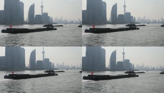 从渡船、摩天大楼和地标建筑上看上海外滩，蓝天背景下，货船在黄浦江上航行，慢镜头。高清在线视频素材下载