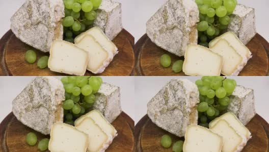 木板上放着一盘发霉的羊奶奶酪和绿葡萄高清在线视频素材下载