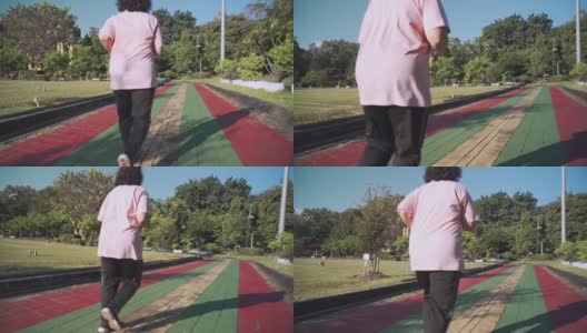 在一个阳光明媚的日子里，亚洲老年肥胖女性在公园的跑道上慢动作跑步。退休生活方式的活动。医疗动机，脉搏血压跟踪，后视镜高清在线视频素材下载