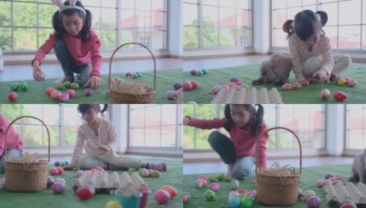 棕兔绕着两个亚洲女孩一起在客厅里玩复活节彩蛋高清在线视频素材下载